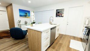 A modern kitchen with a central island, white cabinetry, and a wooden floor. - Your Perfect Oasis in Miami! (Miami)