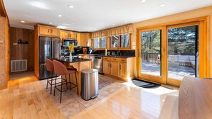 A spacious kitchen with wooden cabinets, stainless steel appliances, and a large window offering a view of the outdoors.