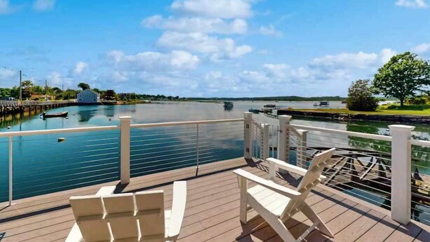 A deck with chairs overlooking a calm body of water, a dock, and a distant shoreline. - Oceanfront Dock Escape ~ Kayaks & Paddleboards (Gloucester)