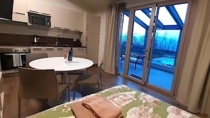 A modern kitchen with a microwave, stove, and dining area with a table and chairs. - Apartment in Iseo With Pool (Cazzago San Martino)