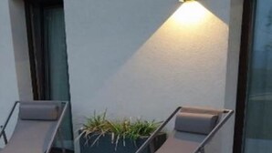 Two lounge chairs with a potted plant between them, positioned against a wall with a window. - Apartment in Iseo With Pool (Cazzago San Martino)