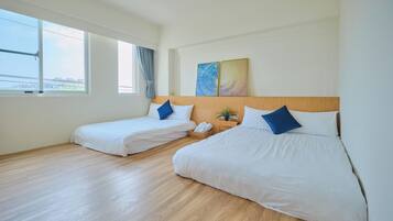 A hotel room with two beds, a wooden headboard, a window with a view, and a painting on the wall.