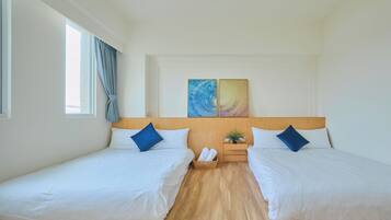 A hotel room with two single beds, a wooden headboard, a small plant, and a window with curtains.