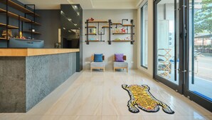 Un área de recepción moderna con mostrador, dos sillas, un felpudo con estampado de tigre y estantes empotrados con adornos.