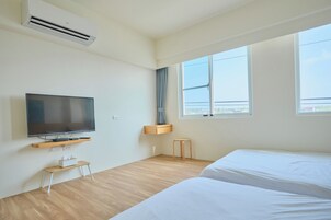 Habitación de hotel con televisión de pantalla plana, un banco de madera, una mesita con pañuelos y una cama.