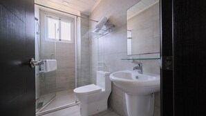 Un baño moderno con cabina de ducha de vidrio, inodoro y lavamanos.