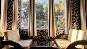 Una habitación con dos sofás, una mesa de centro y un amplio ventanal con cortinas.
