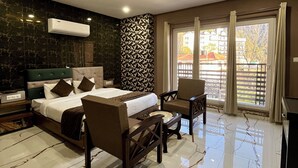 Habitación de hotel con una cama, dos sillones, una mesita, una lámpara en el techo y una ventana con cortinas.