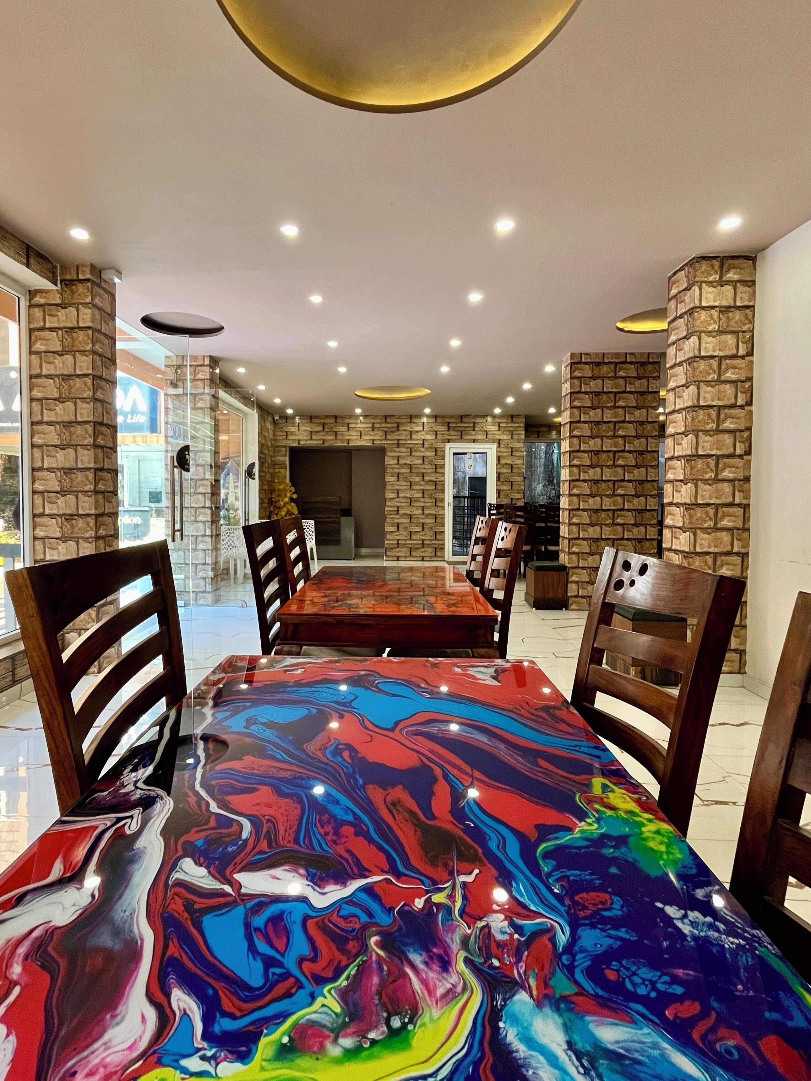 Un espace repas avec une table en marbre, des chaises en bois et un mur décoratif en pierre.