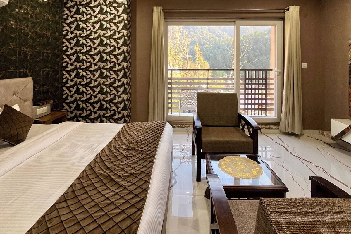 Un dormitorio moderno con una cama grande, un rincón de descanso con una mesa y vistas a un balcón.