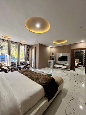 A modern hotel room with a large bed, a flat-screen TV, a minibar, and a seating area with a view of the outdoors. - Viva La Vida Dalhousie (Dalhousie)