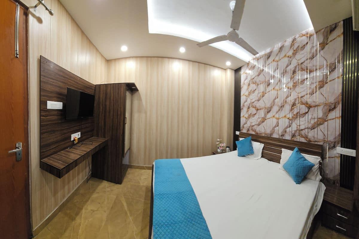 A modern bedroom with a curved ceiling, a bed with blue bedding, a mounted TV, and a marble-patterned wall.