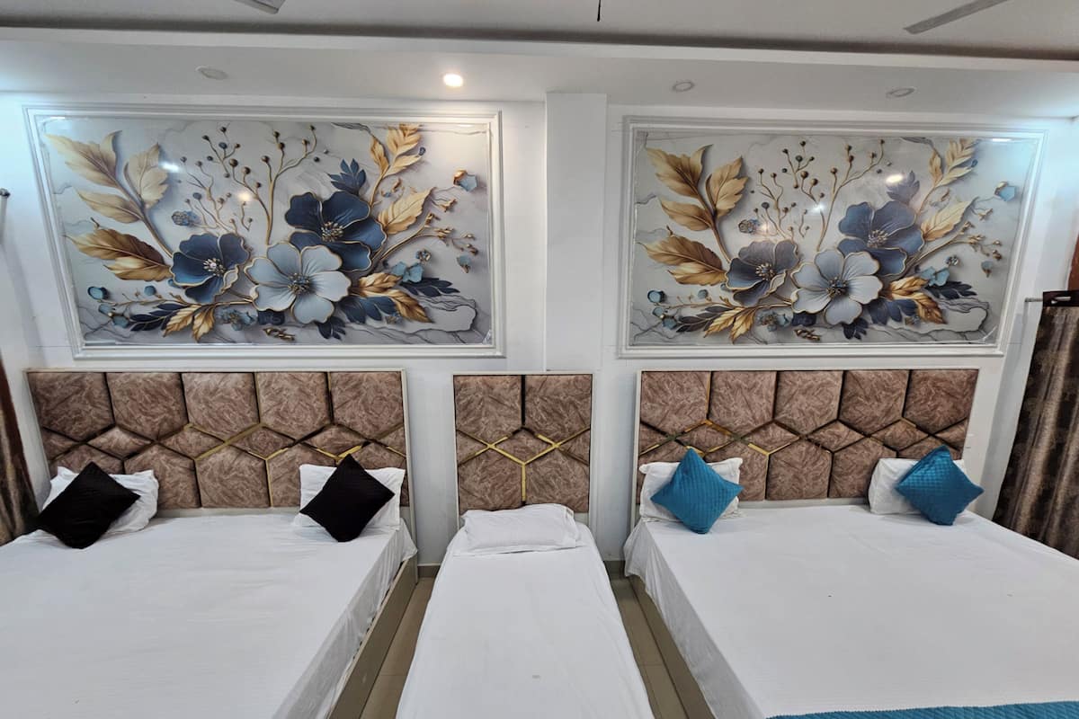 A hotel room with two beds, each with a headboard featuring a geometric pattern. There are floral wall art pieces above the beds and a curtain on the right side.