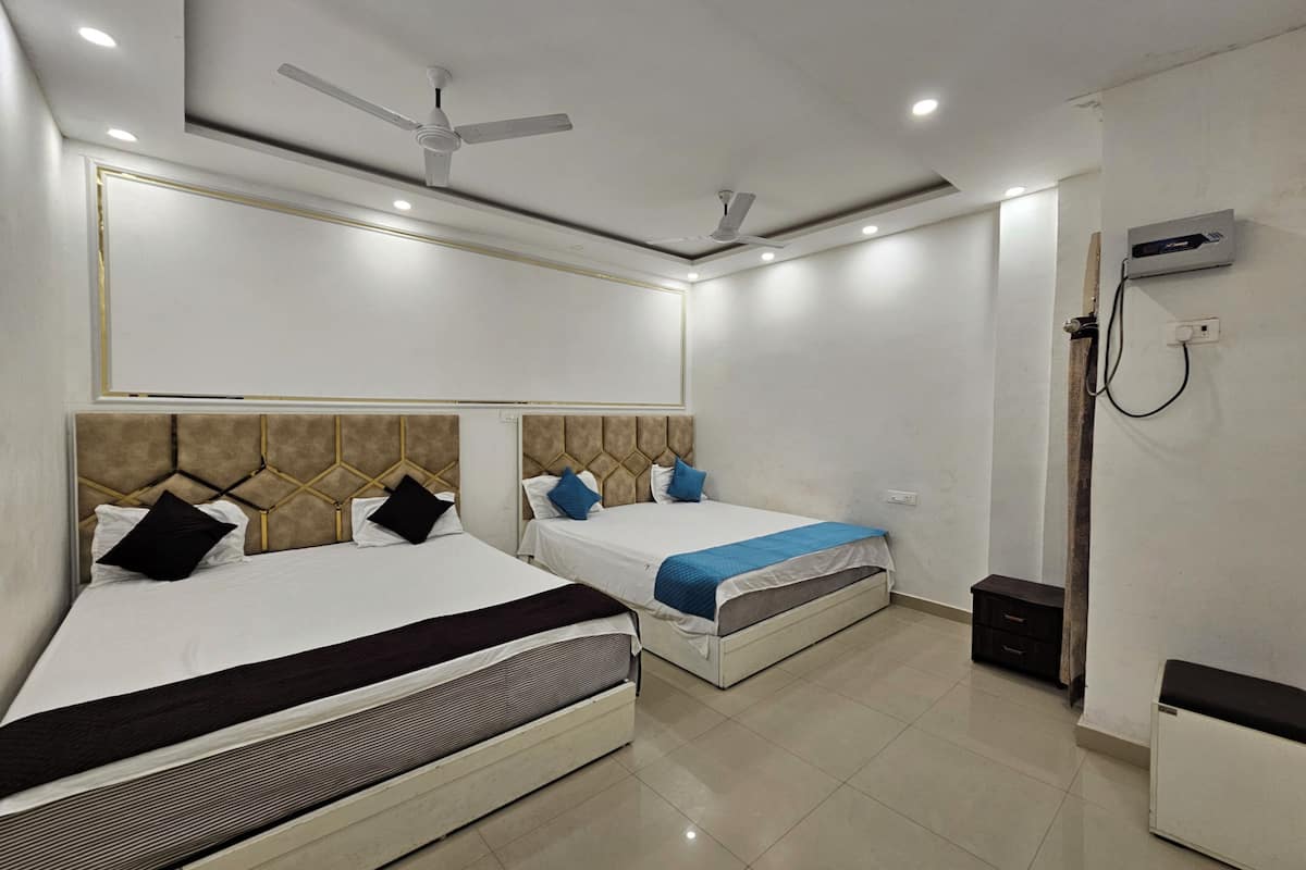 A modern hotel room with two beds, a ceiling fan, recessed lighting, and a built-in air conditioning unit.