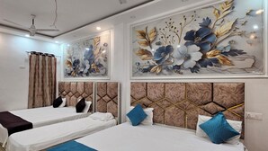 A hotel room with two beds, a ceiling fan, and decorative wall art. - Shivam Guest House (Faizabad)