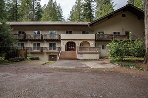 Stunning two-story building with a central entrance and balconies, set amidst a serene lawn and lush greenery.