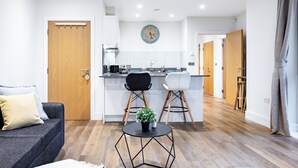 A modern kitchen with a central island, wooden flooring, and a dining area with two chairs. - Cosy 1-bed flat in heart of London Bridge (London)