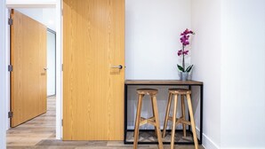 A hallway with wooden flooring, a wooden door, and a small table with two stools and a potted orchid. - Cosy 1-bed flat in heart of London Bridge (London)