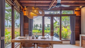 A dining area with a wooden table, two chairs, and a hanging light fixture. - Lumbung Mas Villa by Betterplace (Ubud)