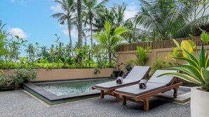 A poolside area with two lounge chairs, a small pool, and lush tropical vegetation. - Lumbung Mas Villa by Betterplace (Ubud)