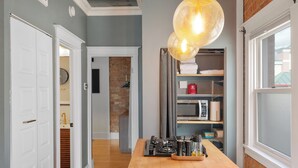 Una cocina con encimera de madera, estufa a gas y lámpara colgante.
