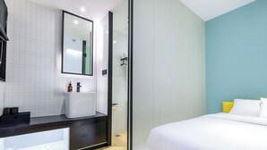 Una habitación de hotel moderna con una cama grande, un baño con espejo y suelo de madera.