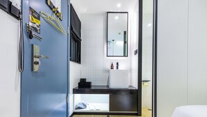 Un baño moderno con puerta azul, un lavabo, un espejo y una zona de ducha.