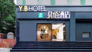 Entrada de hotel con fachada moderna, una escalera visible y un cartel que indica Y.B HOTEL.