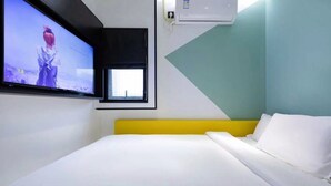 A hotel room with a bed, a TV mounted on the wall, a window, and an air conditioning unit. - YIBAIJIUDIANNANWAITANDIAN (Shanghai)