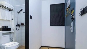A small, modern bathroom with a white toilet, a shower with a black hose, and a wooden floor. - YIBAIJIUDIANNANWAITANDIAN (Shanghai)