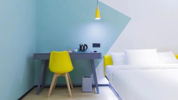 A bedroom with a bed, a desk with a chair, a kettle, and a small heater. - YIBAIJIUDIANNANWAITANDIAN (Shanghai)