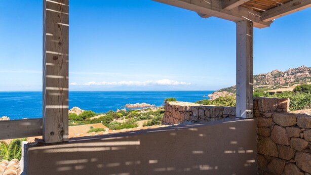 A coastal view from a wooden pergola overlooking the sea and a rocky hillside. - Villa Onda Celeste - Sardinia Unlimited (Costa Paradiso)