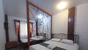 Habitación de hotel con dos camas, un espejo grande y suelo de baldosas de piedra.