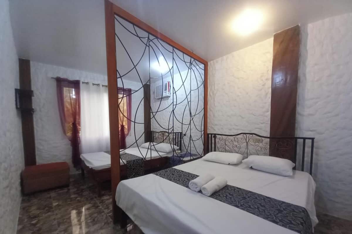 Habitación de hotel con dos camas, un espejo grande y suelo de baldosas de piedra.