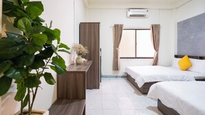 A hotel room with two beds, a wooden desk, a potted plant, and an air conditioning unit. - Phan Hotel (Ho Chi Minh City)