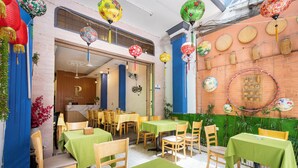 A restaurant with tables and chairs, a brick wall, and hanging decorations. - Phan Hotel (Ho Chi Minh City)