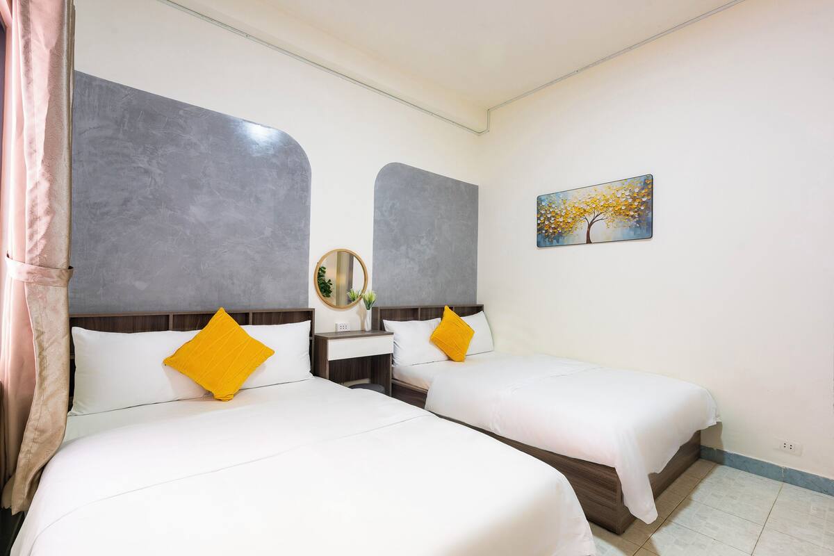 Een hotelkamer met twee bedden, een nachtkastje, een spiegel en een schilderij aan de muur.