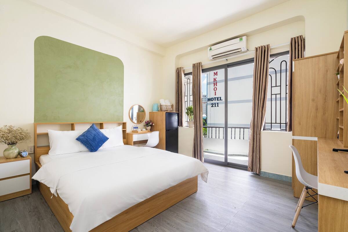Een hotelkamer met een bed, bureau, stoel en uitzicht op het balkon.