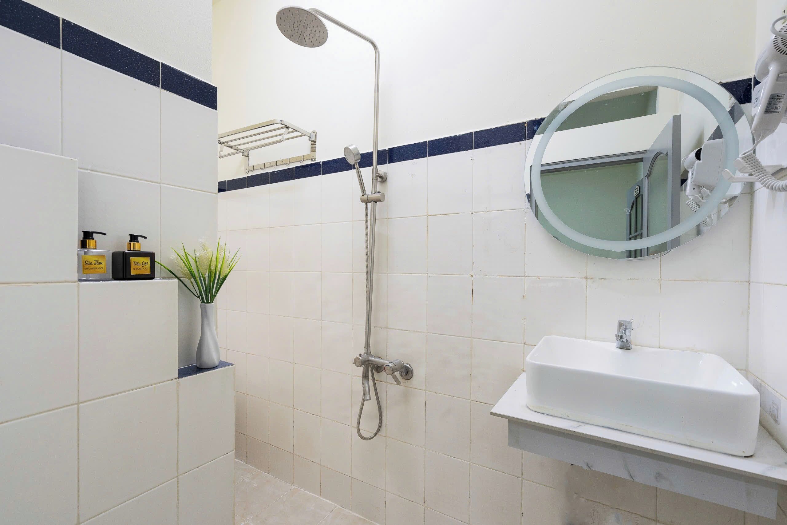 Un baño con ducha, lavamanos y espejo.