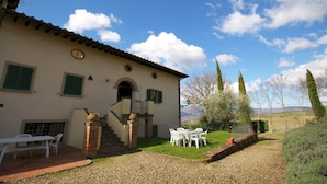 Una villa con un patio, mobiliario exterior y vistas al campo.