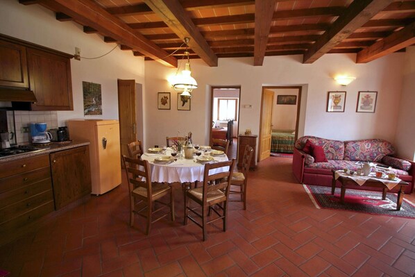 A cozy kitchen with wooden cabinets, a dining table set for four, and a living area with a sofa and a coffee table.