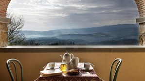 A table with a teapot, cups, and a book, overlooking a mountainous landscape through an arched window. - Apartment in Tuscany near Vineyards (Poppi)