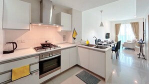 A modern kitchen with a stove, oven, and sink, connected to a dining area with a table and chairs. - Solaris Dutamas by Manhattan Group  (Kuala Lumpur)