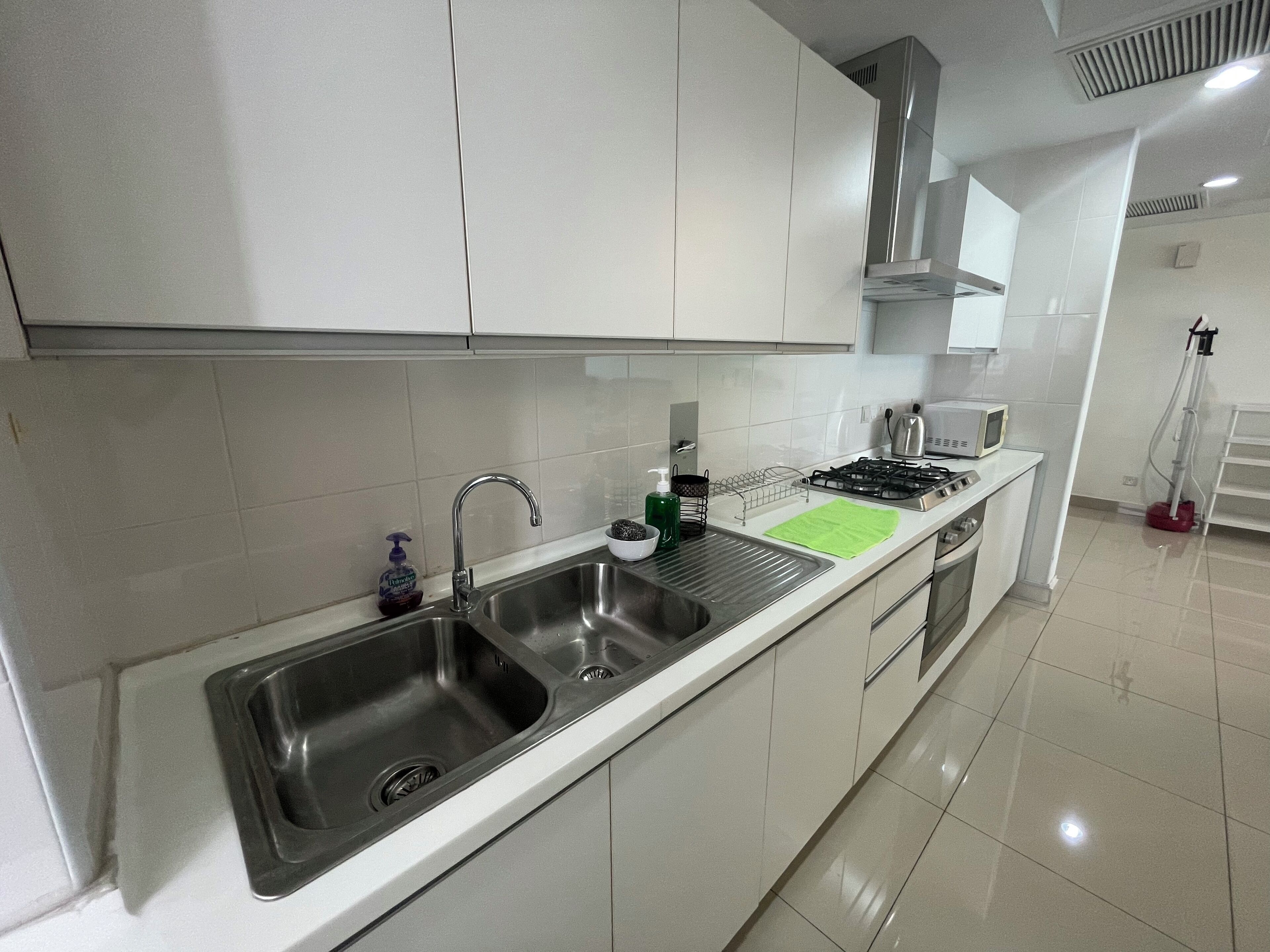 A modern kitchen with a stainless steel sink, a gas stove, and white cabinets.