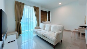 A modern living room with a white sofa, a flat-screen TV, and a large window with curtains. - Solaris Dutamas by Manhattan Group  (Kuala Lumpur)