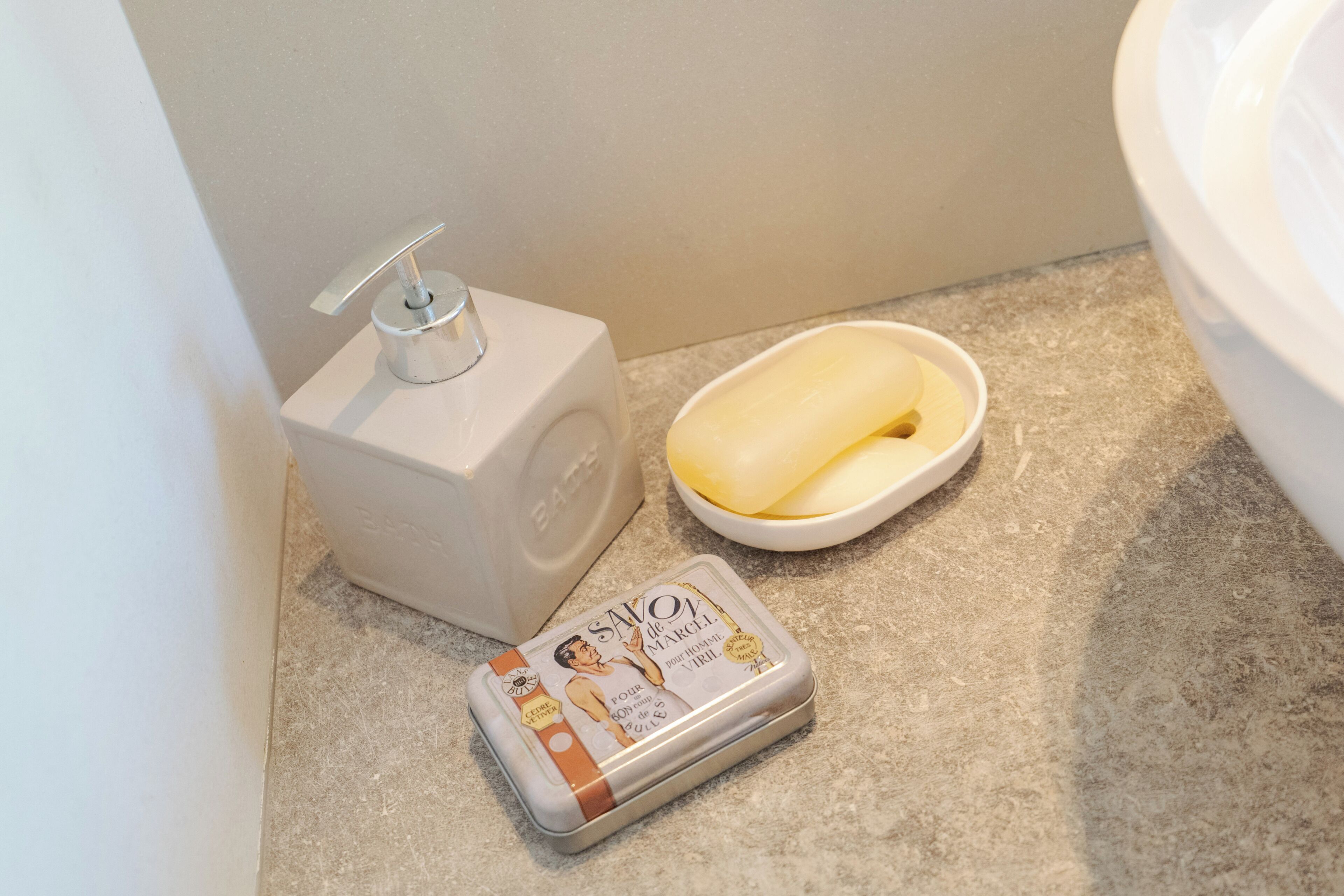 Une salle de bain équipée d’un distributeur de savon, d’un savon en pain et d’une boîte de savon.