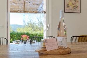A table with a bottle of wine, a card, and a jar on a cork coaster.