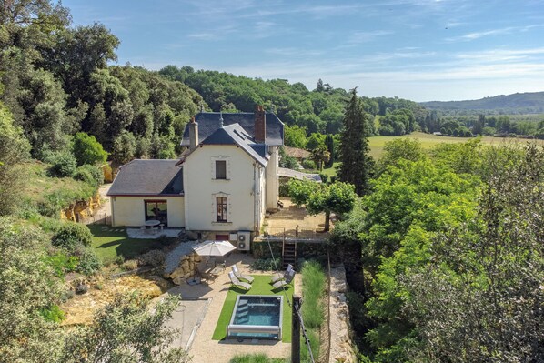 Ein Haus mit Schwimmbad, umgeben von Grünflächen und Hügeln.