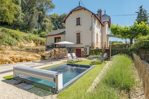 Ein Haus mit Schwimmbecken, Steinmauer und Holzlattenzaun.