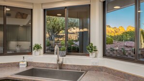 A modern kitchen with a large sink, two potted plants, and a view of a mountainous landscape through large windows. - Carefree on the Rocks  - West Sedona location with a hot tub.  (Sedona)